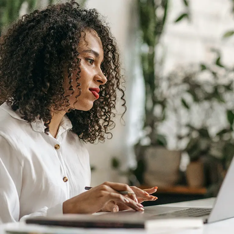 Eine Frau nutzt einen Laptop an ihrem Schreibtisch zur Kommunikation mit der Webagentur SELTENLY.