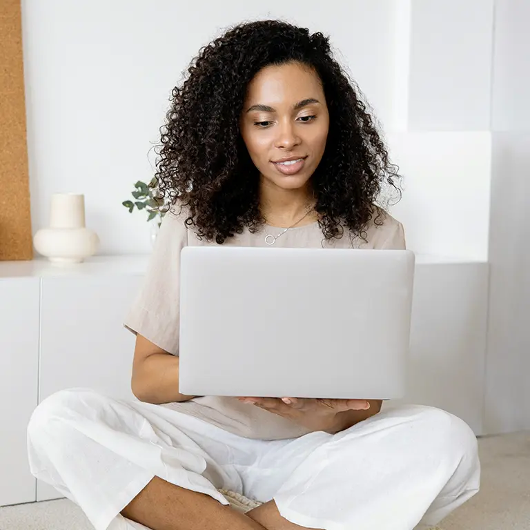 Eine Frau sitzt auf dem Boden und informiert sich am Laptop über die Webagentur SELTENLY aus Graz.